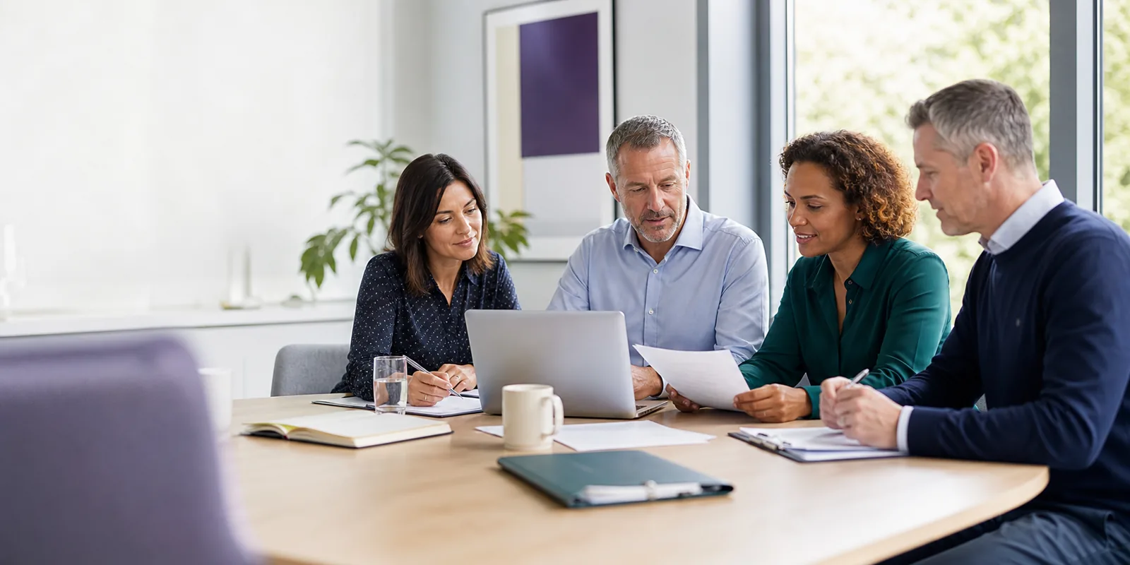 A registered manager and colleagues reviewing documents around a table with a consultant